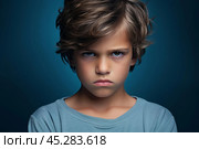 Portrait of disgruntled blond boy against blue background. The boy experiencing negative emotions due to fact that his family tore him away from computer games and forced him. Sulking Caucasian boy. Стоковое AI-изображение, AI-художник Sergey Grishin / Фотобанк Лори