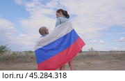 A boy with a woman in a field with a Russian flag on their shoulders. National holiday independence day. Pride and patriotism. Стоковое видео, видеограф Екатерина Золина / Фотобанк Лори