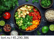 Colorful fresh salad ingredients arranged in a bowl with lime and herbs on a dark surface. Стоковое AI-изображение, AI-художник Юлия Гапеенко / Фотобанк Лори
