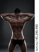 Handsome muscular bodybuilder posing on gray background. Low key studio shot. Стоковое фото, фотограф Станислав Тарко / Фотобанк Лори