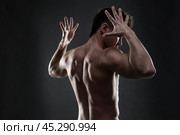 Handsome muscular bodybuilder posing on gray background. Low key studio shot. Стоковое фото, фотограф Станислав Тарко / Фотобанк Лори