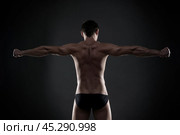 Handsome muscular bodybuilder posing on gray background. Low key studio shot. Стоковое фото, фотограф Станислав Тарко / Фотобанк Лори
