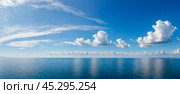 Wide view shows quiet sea under big sky at nightfall. Soft waves move on ocean top, showing off dim light. Up high, clouds move, colored with sunset shades, giving feel of quiet and endlessness. Стоковое фото, фотограф Павел Муравьев / Фотобанк Лори