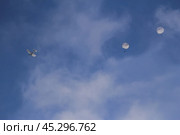 A small aircraft is seen in a bright blue sky, dispersing parachutes that drift downwards. Стоковое фото, фотограф Алексей Климкин / Фотобанк Лори