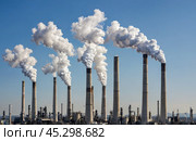 Tall smokestacks emit thick smoke, polluting air over industrial area, environmental concern. atmospheric contamination evident over urban landscape. Стоковое AI-изображение, AI-художник Павел Муравьев / Фотобанк Лори