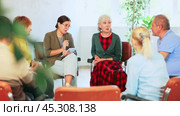 Group of elderly people communicating in English-speaking club with young female tutor. Стоковое видео, видеограф Яков Филимонов / Фотобанк Лори
