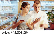 Positive young girl purchaser scanning QR code on bottle of milk standing in supermarket with varied stock. Стоковое видео, видеограф Яков Филимонов / Фотобанк Лори