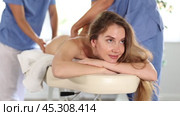 Back massage in four hands simultaneously - two professional masseurs treating young woman. Стоковое видео, видеограф Яков Филимонов / Фотобанк Лори