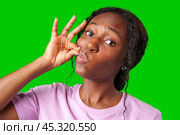 A young woman in a pink shirt makes a shushing gesture against a bright green background. Стоковое фото, фотограф Сергей Толмачёв / Фотобанк Лори