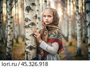 A beautiful girl in a traditional Russian folk shawl in a spring birch grove. The portrait symbolizes the traditions and beauty of the Russian people. Стоковое AI-изображение, AI-художник Photojuli / Фотобанк Лори