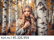 A beautiful girl in a traditional Russian folk shawl in a autumn birch grove. The portrait symbolizes the traditions and beauty of the Russian people. Стоковое AI-изображение, AI-художник Photojuli / Фотобанк Лори