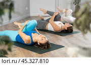 Woman doing Ardha Pawanmuktasana with group in yoga studio. Стоковое фото, фотограф Яков Филимонов / Фотобанк Лори