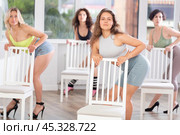 Group of girls unleash their energy and dance passionately near a chair in high heels in a dance studio. His powerful moves combined with elegance of high heels. Стоковое фото, фотограф Яков Филимонов / Фотобанк Лори