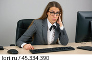 Unhappy woman in office attire at desk with unenthusiastic expression, surrounded by computer, keyboard, mouse, indicating job dissatisfaction and corporate monotony. Стоковое AI-изображение, AI-художник Павел Муравьев / Фотобанк Лори