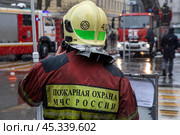 Сотрудник пожарного расчета принимает участие в тушении пожара в центре города Москвы, Россия. Редакционное фото, фотограф Николай Винокуров / Фотобанк Лори