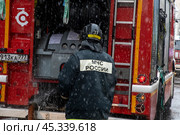 Сотрудник пожарного расчета принимает участие в тушении пожара в центре города Москвы, Россия. Редакционное фото, фотограф Николай Винокуров / Фотобанк Лори