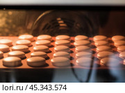 Половинки макарун в духовке. Приготовление сладостей в домашних условиях. Кондитерские изделия выпекаются в духовном шкафу. Стоковое фото, фотограф Евгений Зимин / Фотобанк Лори