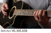 Playing the guitar. Strumming acoustic guitar. Musician plays music. Man fingers holding mediator. Man hand playing guitar neck in dark room. Unrecognizable person rehearsing, fretboard close-up. Стоковое видео, видеограф Марина Демидюк / Фотобанк Лори