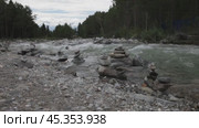 Video of a fast flowing mountain river with stone pyramids of tourists on the shore. Стоковое видео, видеограф Виктория Катьянова / Фотобанк Лори