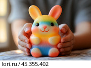 Яркая разноцветная игрушка в ладонях. Стоковое AI-изображение, AI-художник Щеголева Ольга / Фотобанк Лори