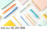 Colorful stationery arranged on a white background, featuring notebooks, pens, and highlighters in various hues. Стоковое AI-изображение, AI-художник Сергей Толмачёв / Фотобанк Лори