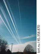 Chemtrail conspiracy theory. Long-lasting condensation trails left in sky by high-flying aircraft are actually chemtrails consisting of chemical or biological agents, sprayed for nefarious purposes. Стоковое AI-изображение, AI-художник Юлия Петровская / Фотобанк Лори