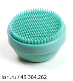 A green, silicone facial scrubber with soft, fine bristles. The compact, round design is simple and functional, intended for gentle exfoliation and skincare routines. Стоковое AI-изображение, AI-художник Ольга Игнашина / Фотобанк Лори