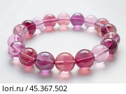 Pink quartzite bracelet resting on white background. Стоковое AI-изображение, AI-художник Иван Рябоконь / Фотобанк Лори
