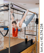 Man performing hanging back lever on Pilates trapeze table. Стоковое фото, фотограф Яков Филимонов / Фотобанк Лори
