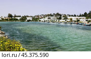 Serene view of blue waters and neatly moored boats along coastline near Punic Ports in Carthage, against backdrop of modern city architecture under Tunisian sun. Стоковое видео, видеограф Яков Филимонов / Фотобанк Лори