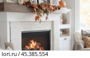 Cozy autumn living room featuring a decorated fireplace with seasonal foliage and family photos on the mantel. Стоковое AI-изображение, AI-художник Сергей Толмачёв / Фотобанк Лори