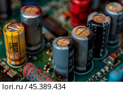 Electrolytic capacitors standing on green circuit board. Стоковое AI-изображение, AI-художник Иван Рябоконь / Фотобанк Лори