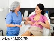 Plastic surgeon and woman discussing procedure of breast augmentation during consultation. Стоковое фото, фотограф Яков Филимонов / Фотобанк Лори