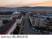 Утренний городской пейзаж. Вид с воздуха на город на рассвете. Вид сверху на здания и пустую улицу. Сопки вдалеке. Улица Парковая, город Магадан, Магаданская область, Дальний Восток России. Стоковое фото, фотограф Андрей Степанов / Фотобанк Лори