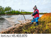 Мальчик с рыболовной сетью у реки. Его отец рядом, а он, познает мир - повторяет все движения отца . Их родовое имение находится в лесу ( недалеко от реки ). Они, коренные жители народов севера - ханты, здесь живут годами. Основные продукты - самые, что ни на есть натуральные. Все остальное покупают раз в месяц, в городе. Сообщение с городом круглый год по реке , километров 20-25... (2011 год). Редакционное фото, фотограф Павел Просянов / Фотобанк Лори