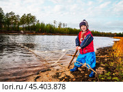 Мальчик с рыболовной сетью у реки. Его отец рядом, а он, познает мир - повторяет все движения отца . Их родовое имение находится в лесу ( недалеко от реки ). Они, коренные жители народов севера - ханты, здесь живут годами. Основные продукты - самые, что ни на есть натуральные. Все остальное покупают раз в месяц, в городе. Сообщение с городом круглый год по реке , километров 20-25... (2011 год). Редакционное фото, фотограф Павел Просянов / Фотобанк Лори