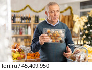 Retired man chooses panellets for a holiday table in supermarket. Стоковое фото, фотограф Яков Филимонов / Фотобанк Лори