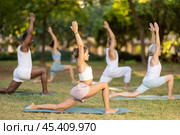 Girl performing Anjaneyasana during group yoga outdoors. Стоковое фото, фотограф Яков Филимонов / Фотобанк Лори