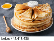 Stack of traditional russian pancakes blini with honey and sour creamon gray background. Стоковое фото, фотограф Наталия Попова / Фотобанк Лори
