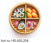 Разнообразные суши, роллы и нигири, красиво поданные в бамбуковой пароварке на белом фоне, подчеркивают традиционную японскую кухню. Стоковое AI-изображение, AI-художник ФотоИнтеллект / Фотобанк Лори