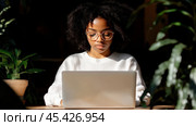 Концентрированная афроамериканская деловая женщина, работающая на ноутбуке в солнечном офисе. Стоковое AI-изображение, AI-художник ФотоИнтеллект / Фотобанк Лори