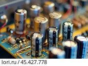 Electrolytic capacitors standing on circuit board in close up. Стоковое AI-изображение, AI-художник Иван Рябоконь / Фотобанк Лори