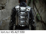 Man wearing suit of armor standing in front of stone wall. Стоковое AI-изображение, AI-художник Иван Рябоконь / Фотобанк Лори