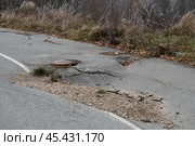 Pothole damage on a rural road surrounded by trees in autumn highlights urgent need for repairs. Стоковое фото, фотограф Георгий Мякишев / Фотобанк Лори
