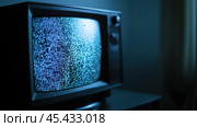 Старинный телевизор, показывающий помехи в темной комнате, символизирующий конец свободы слова и цензуры в СМИ. Стоковое AI-изображение, AI-художник ФотоИнтеллект / Фотобанк Лори