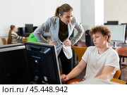 Strict teacher reprimanding negligent teenage student in computer class. Стоковое фото, фотограф Яков Филимонов / Фотобанк Лори