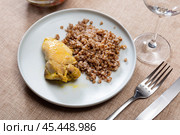 Prepared buckwheat porridge with piece of fried chicken is served on large white platter. Стоковое фото, фотограф Яков Филимонов / Фотобанк Лори