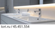 Modern bathroom vanity with double sinks and chrome faucets illuminating wellness. Стоковое AI-изображение, AI-художник Юрий Поздников / Фотобанк Лори
