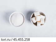 Choosing between granulated sugar and refined sugar in bowls on white background. Стоковое фото, фотограф Елена Руй / Фотобанк Лори