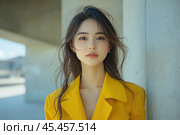 Portrait of a girl against a backdrop of a modern architectural landscape. She is wearing a stylish yellow jacket that attracts attention and emphasizes her elegance. Her hair is slightly blown by the wind, creating dynamism and a sense of freshness. Her gaze is directed straight at the camera, radiating confidence and calm. The lighting is soft, with natural daylight highlighting her facial features. The background is blurred, which adds depth and focuses attention on the model. This photo is perfect for themes related to fashion, lifestyle, modern femininity and positive mood. Стоковое AI-изображение, AI-художник Анна Кривицкая / Фотобанк Лори